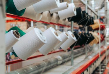 Detailed view of yarn spools in a textile factory, showcasing industrial equipment.